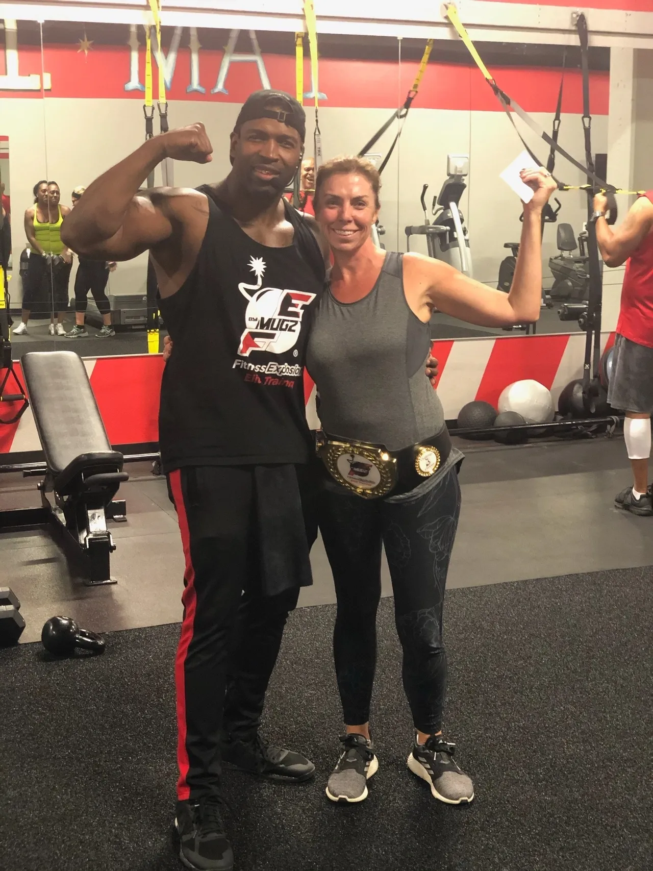 Coach Mugz celebrating with member holding championship belt