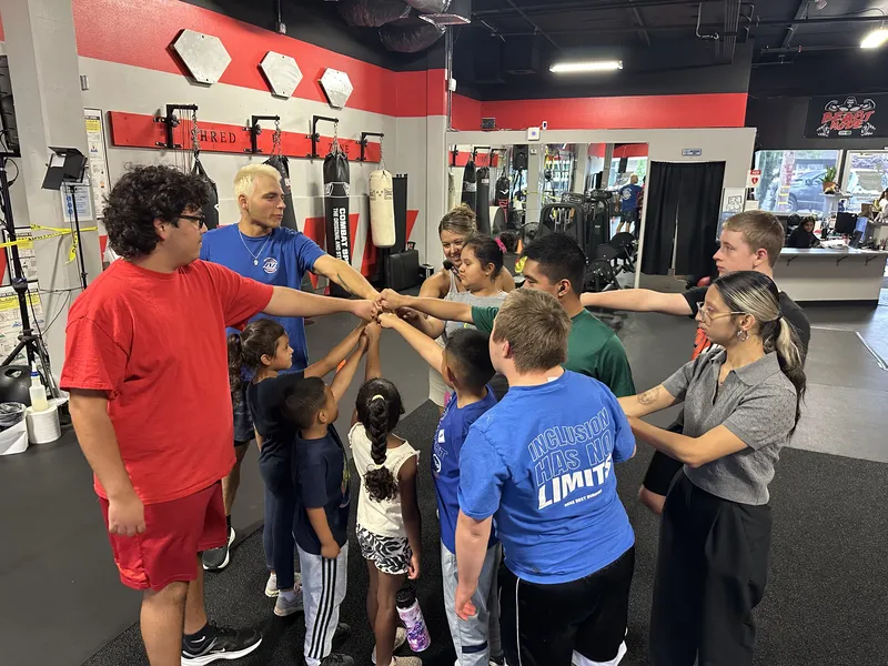 Coach Mugz in a team huddle with members at Fitness Explosion