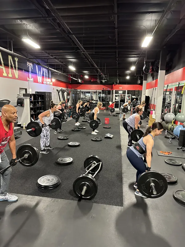 Bootcamp class — full gym with members doing barbell work