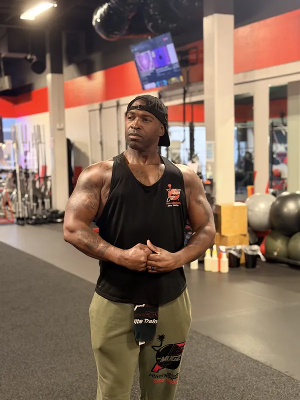 Coach Mugz standing on the gym floor in FE branded gear