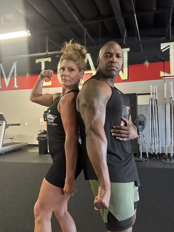 Coach Mugz and member back-to-back power flex in the gym