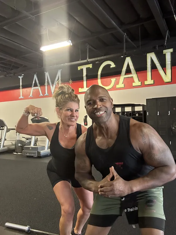 Coach Mugz and member flexing and smiling together