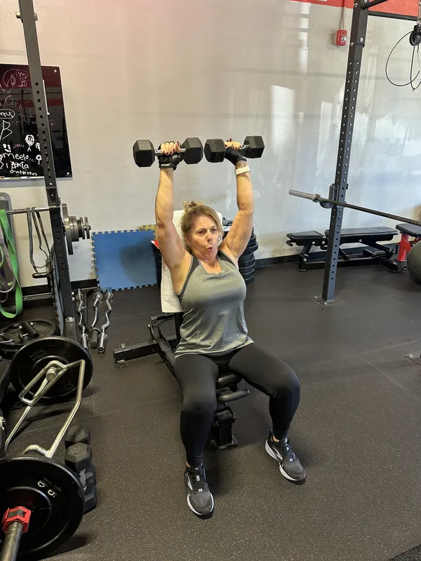 Member doing seated shoulder press with dumbbells
